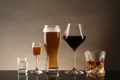 Photo of Glasses with different alcoholic drinks on table against beige background