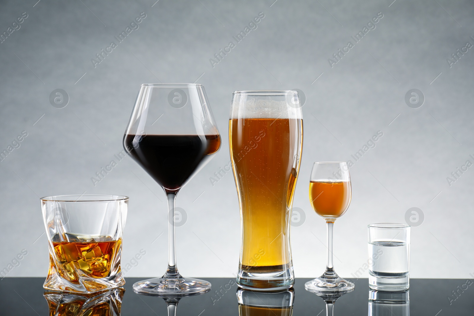 Photo of Glasses with different alcoholic drinks on table against light gray background