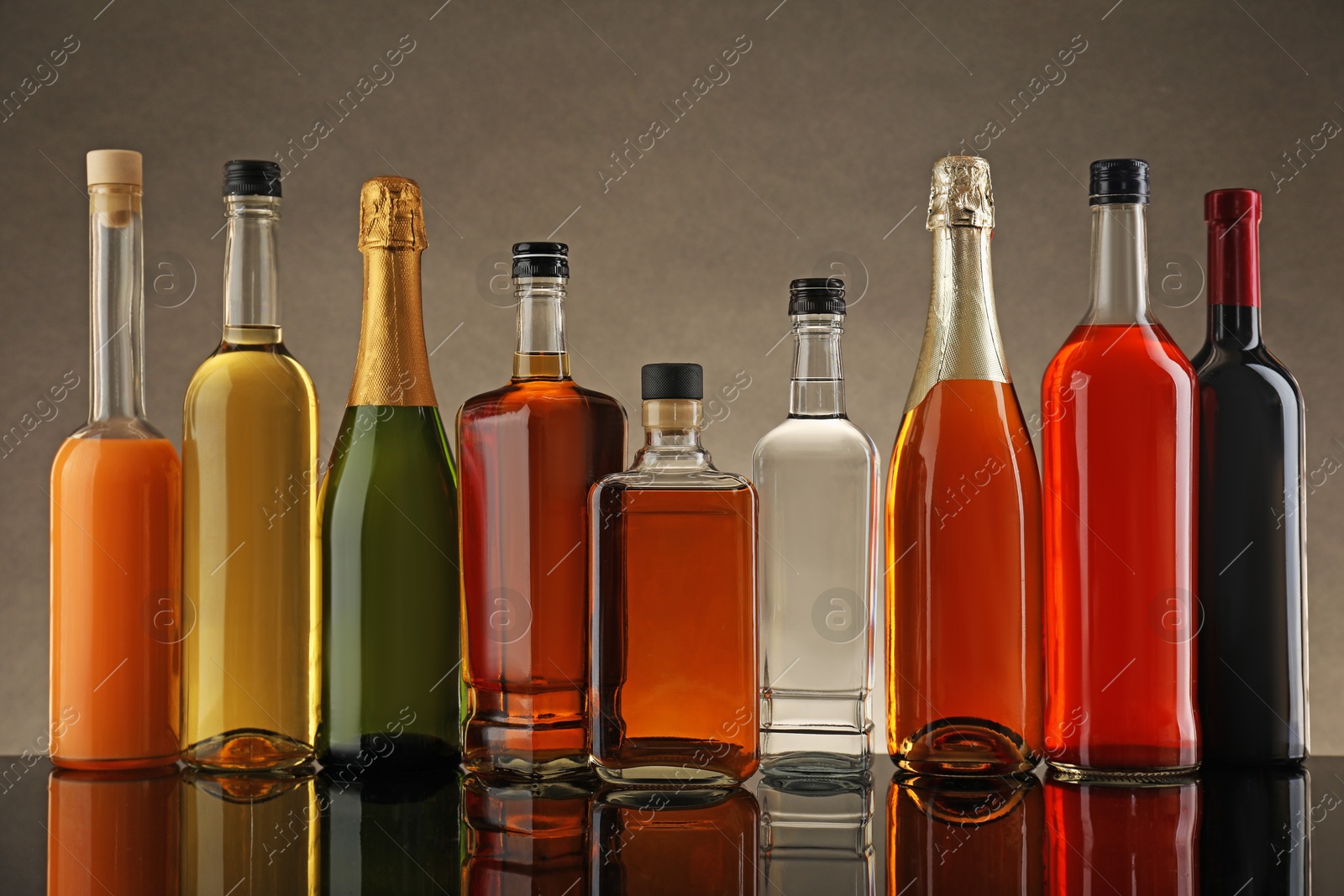 Photo of Bottles of different alcoholic drinks on table against gray background