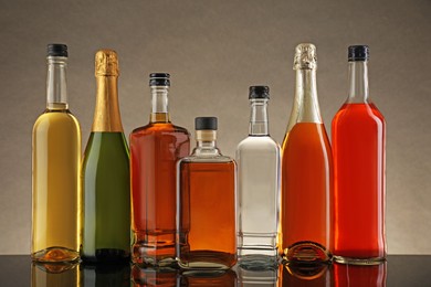 Photo of Bottles of different alcoholic drinks on table against gray background