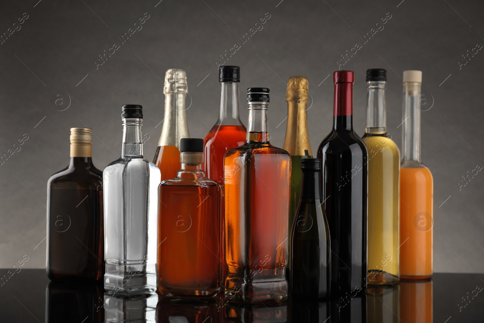 Photo of Bottles of different alcoholic drinks on table against gray background