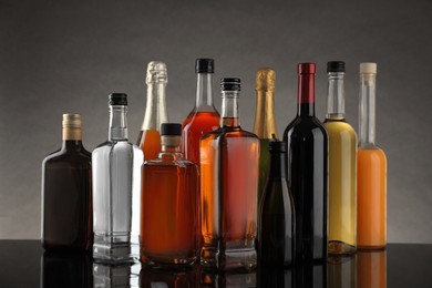 Bottles of different alcoholic drinks on table against gray background