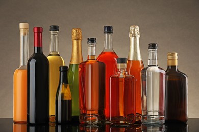 Photo of Bottles of different alcoholic drinks on table against gray background