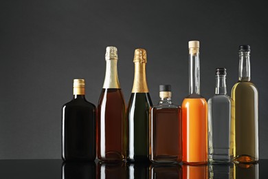 Bottles of different alcoholic drinks on table against gray background