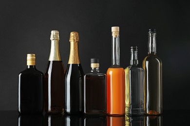 Bottles of different alcoholic drinks on black background