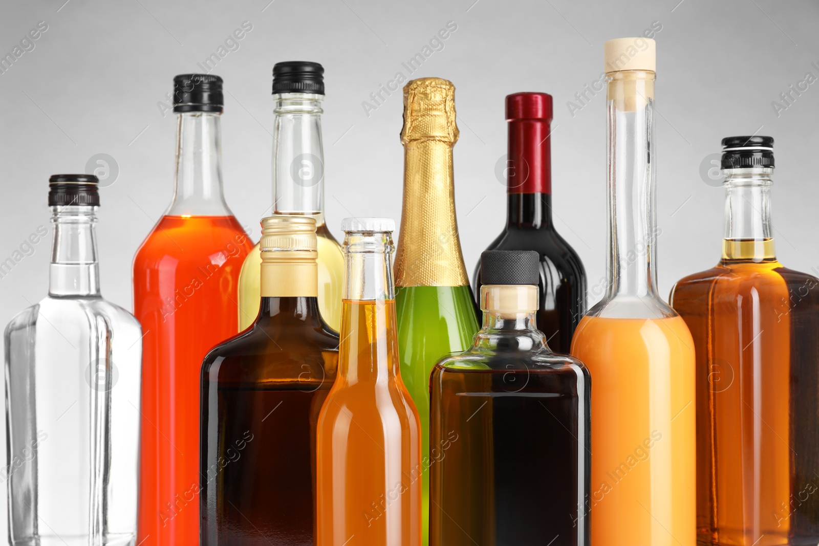 Photo of Bottles of different alcoholic drinks on gray background, closeup