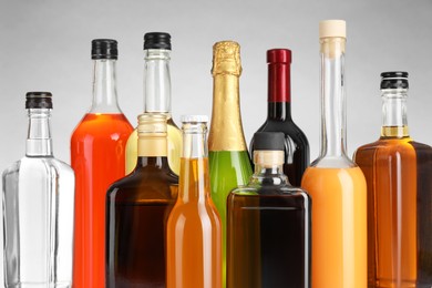 Bottles of different alcoholic drinks on gray background, closeup