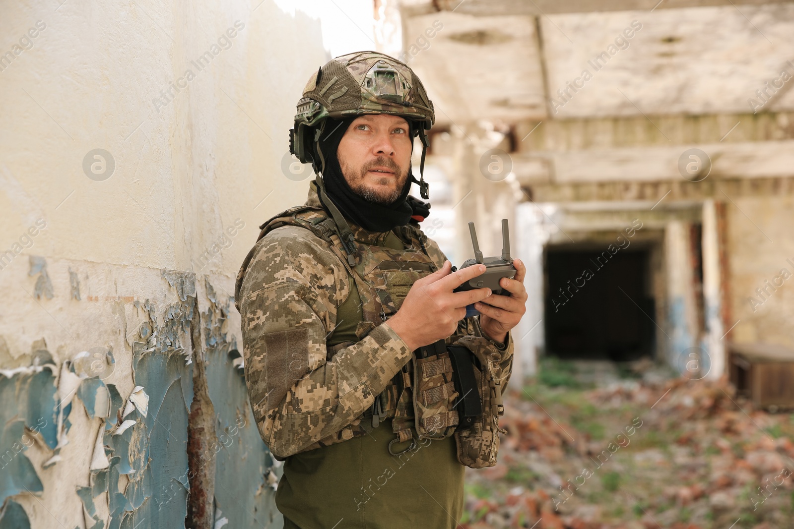 Photo of Military mission. Soldier in uniform with drone controller inside abandoned building