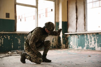 Military mission. Soldier in uniform inside abandoned building, space for text