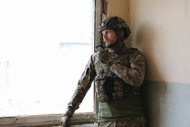 Military mission. Soldier in uniform with radio transmitter inside abandoned building, space for text