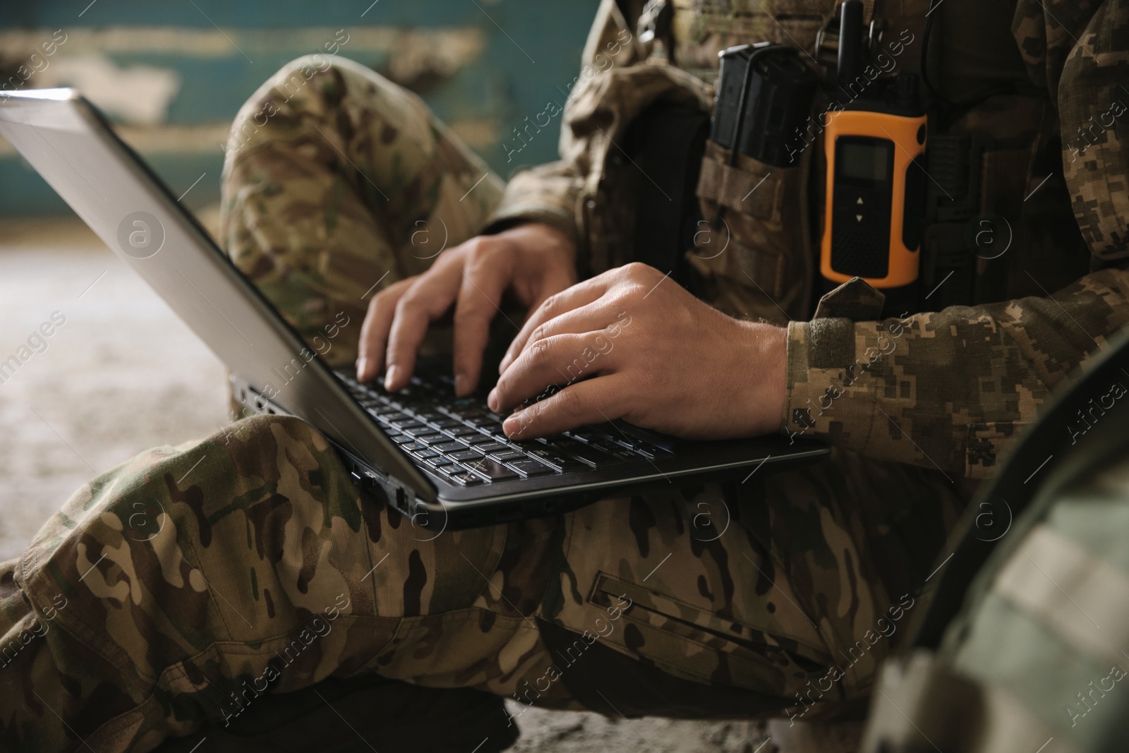 Photo of Military mission. Soldier in uniform using laptop inside abandoned building, closeup