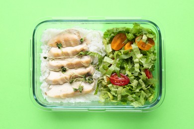 Photo of Healthy meal. Fresh salad, rice and chicken in glass container on green background, top view