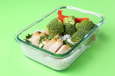 Healthy meal. Fresh broccoli, chicken and rice in glass container on green background