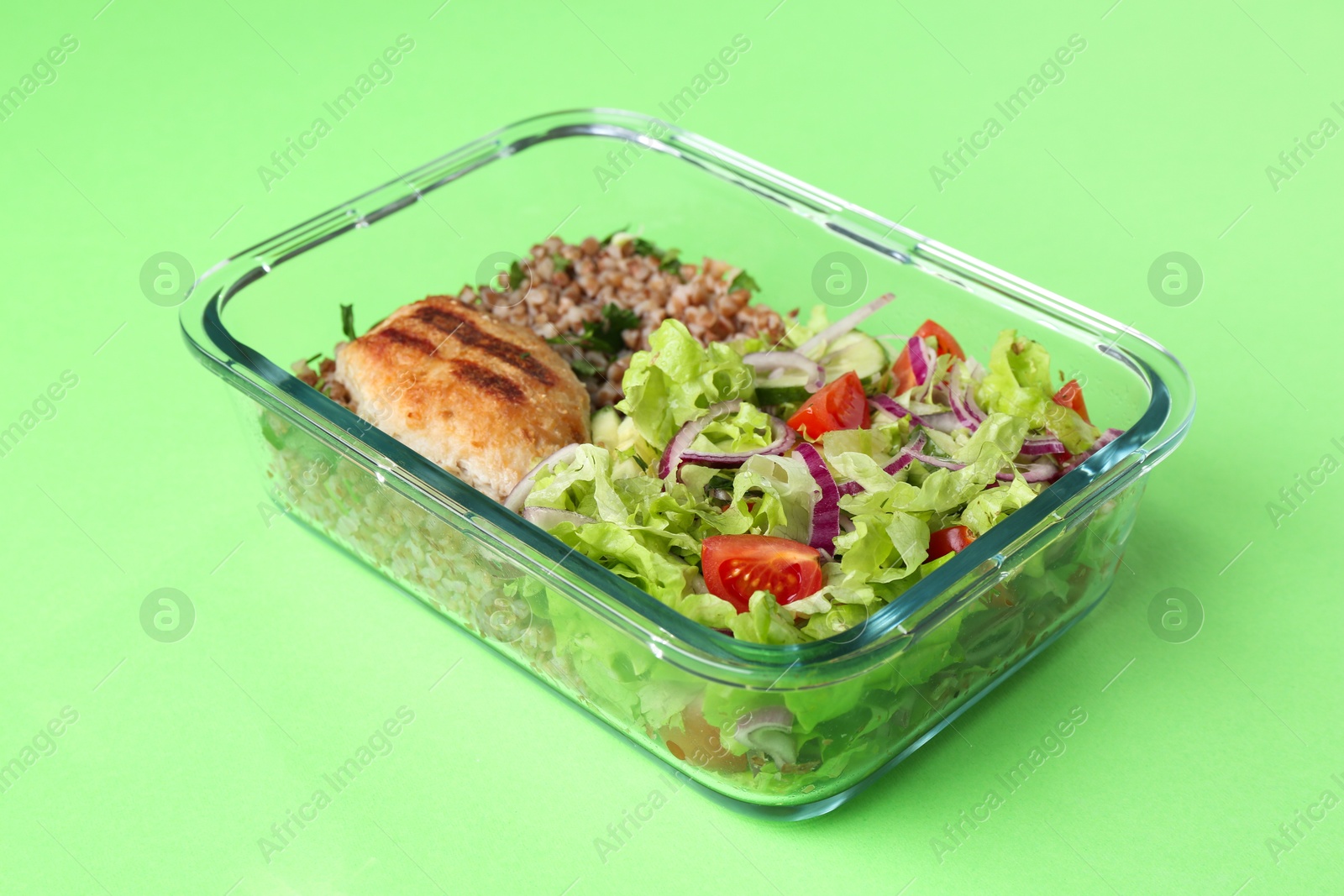 Photo of Healthy meal. Fresh salad, cutlet and buckwheat in glass container on green background