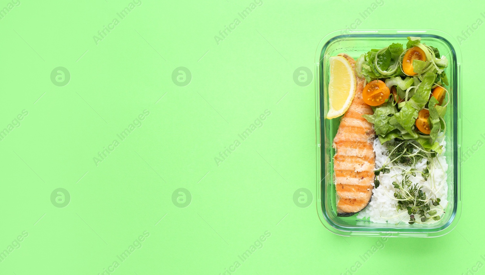 Photo of Healthy meal. Fresh salad, salmon and rice in glass container on green background, top view. Space for text