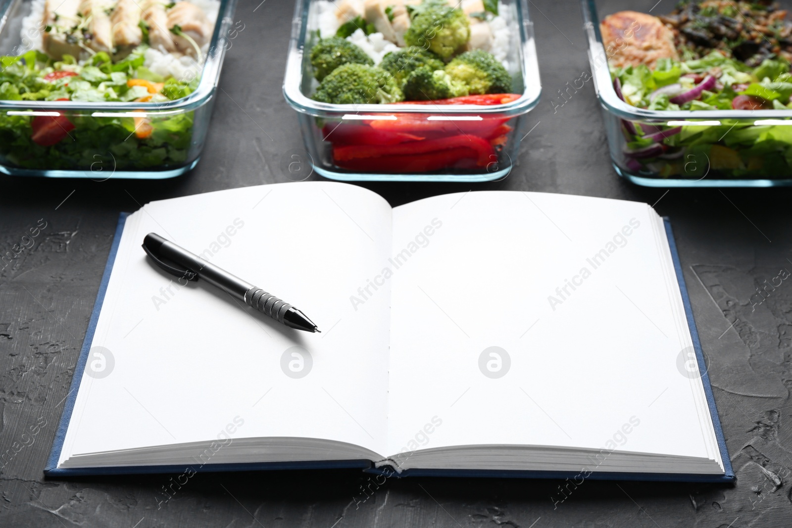 Photo of Healthy food. Open notebook, pen and different meals on black table