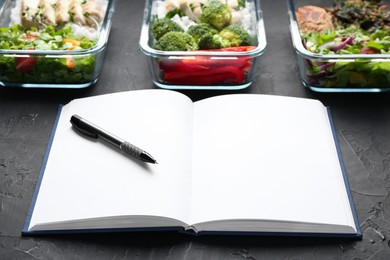 Healthy food. Open notebook, pen and different meals on black table