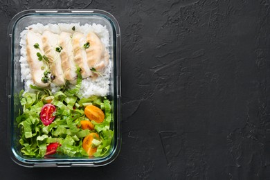 Healthy meal. Fresh salad, chicken and rice in glass container on black table, top view. Space for text