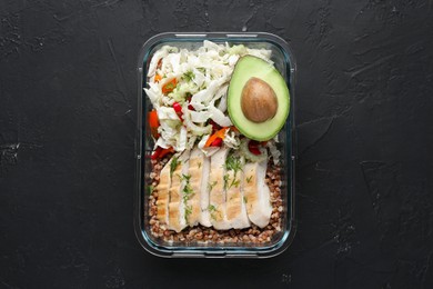 Healthy meal. Fresh salad, avocado, chicken and buckwheat in glass container on black table, top view