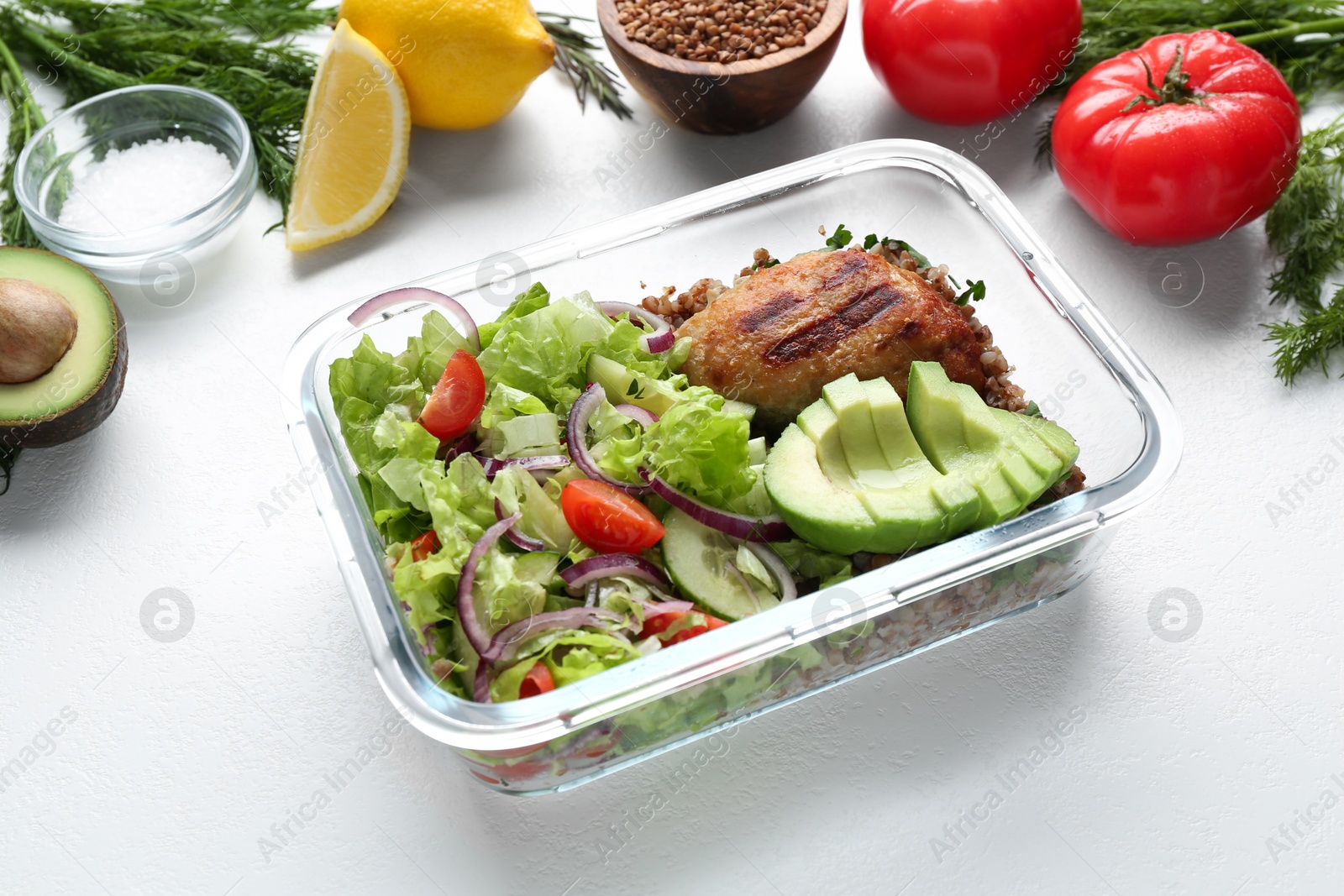 Photo of Healthy meal. Fresh salad, avocado and cutlet in glass container near other products on white background