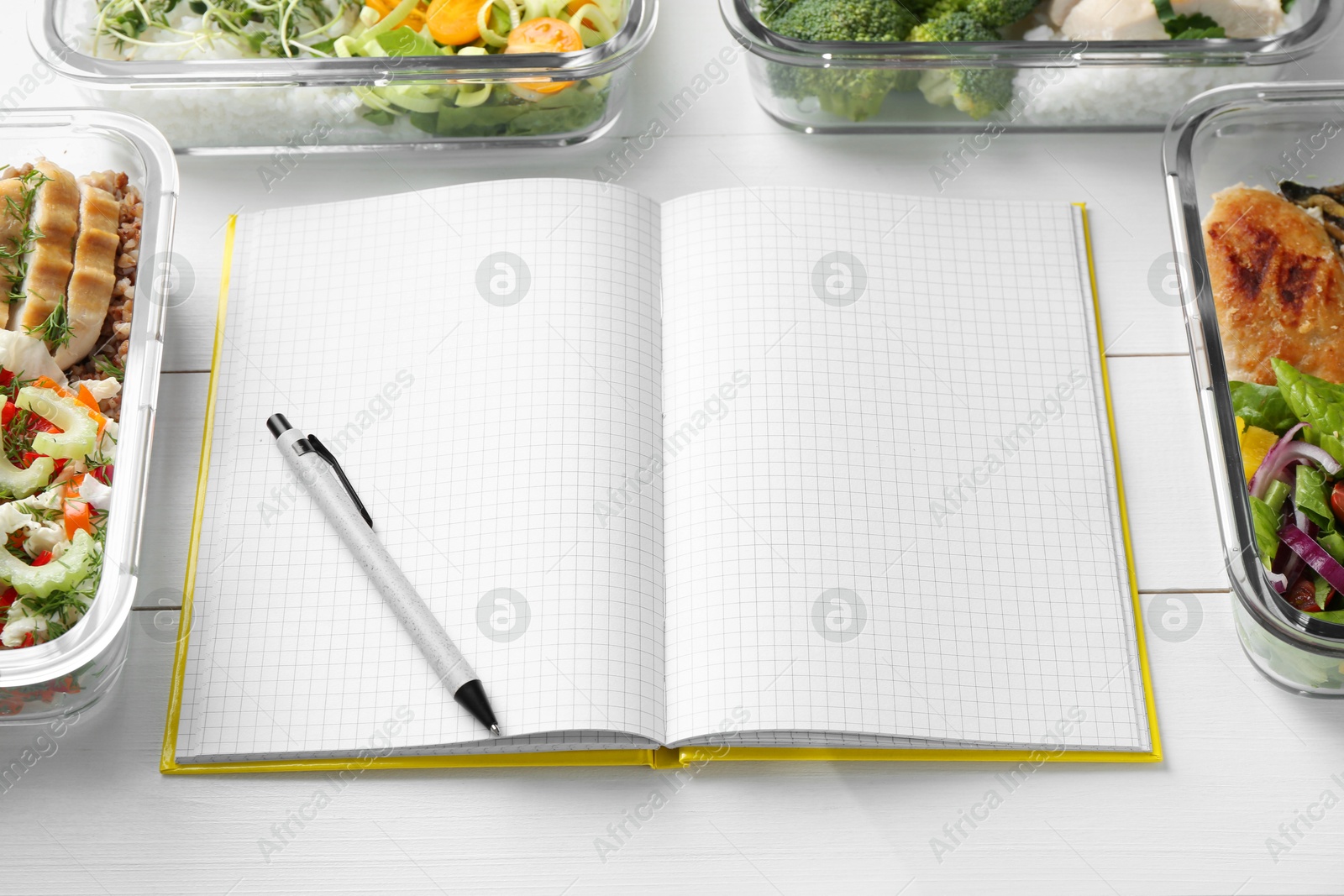 Photo of Healthy meal. Open notebook and containers with different products on white wooden table