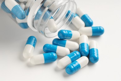 Photo of Antibiotic pills and bottle on white background, closeup