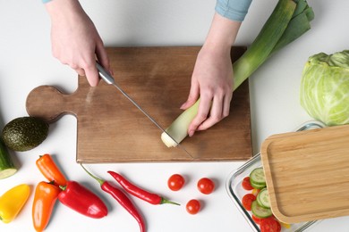 Healthy food. Woman cutting leek at white table, top view