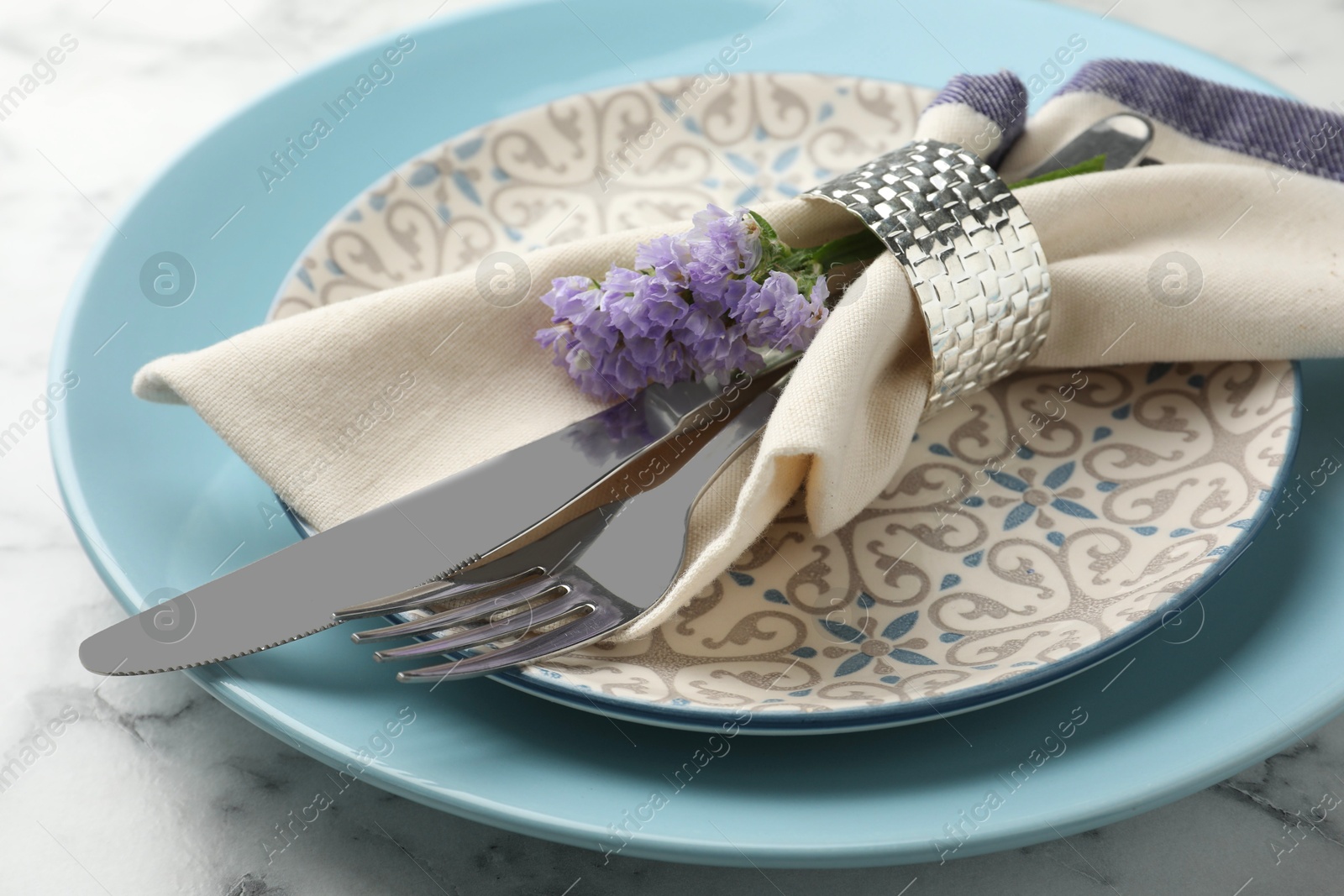 Photo of Stylish setting with cutlery and plates on white marble table, closeup