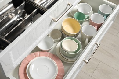 Ceramic dishware and cutlery in drawers indoors