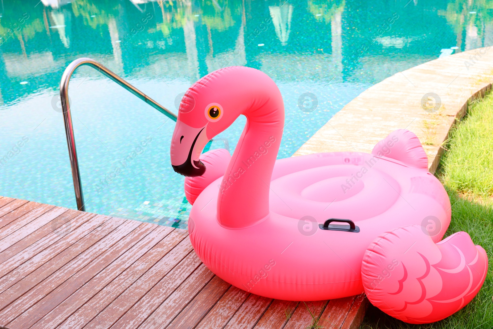 Photo of Float in shape of flamingo on wooden deck near swimming pool at luxury resort