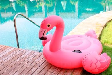 Float in shape of flamingo on wooden deck near swimming pool at luxury resort