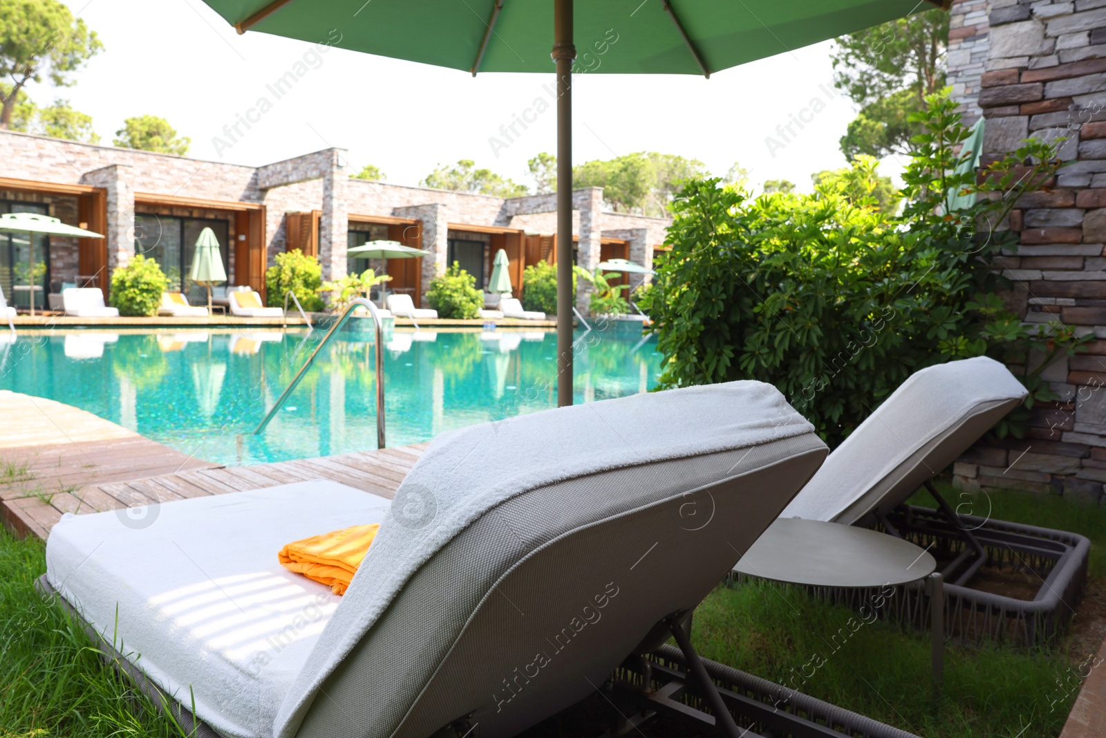 Photo of Sunbeds near outdoor swimming pool at luxury resort