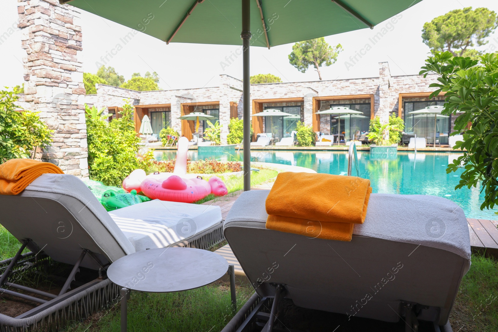 Photo of Sunbeds near outdoor swimming pool at luxury resort