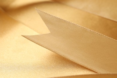Photo of Beautiful golden ribbon as background, closeup view