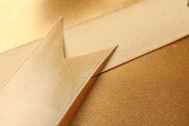 Photo of Beautiful golden ribbon as background, closeup view