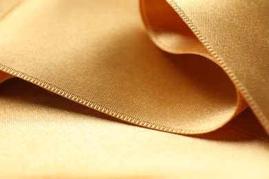 Photo of Beautiful golden ribbon as background, closeup view