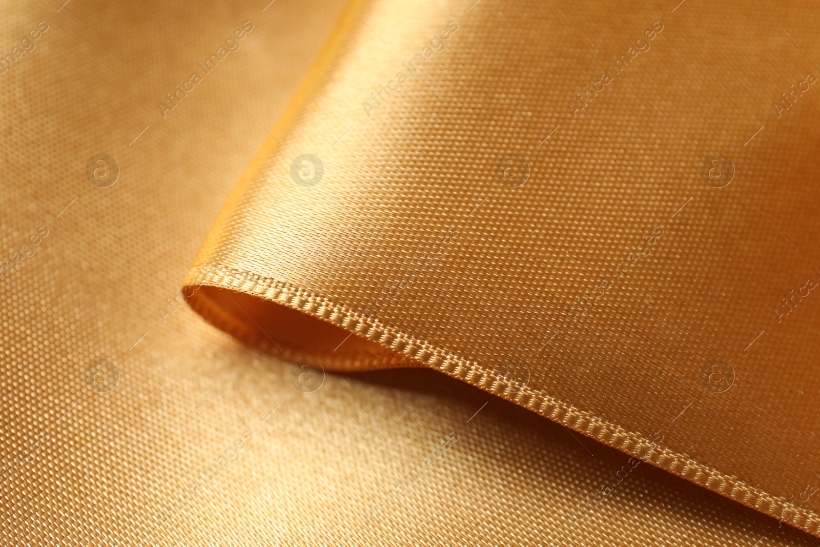 Photo of Beautiful golden ribbon as background, closeup view