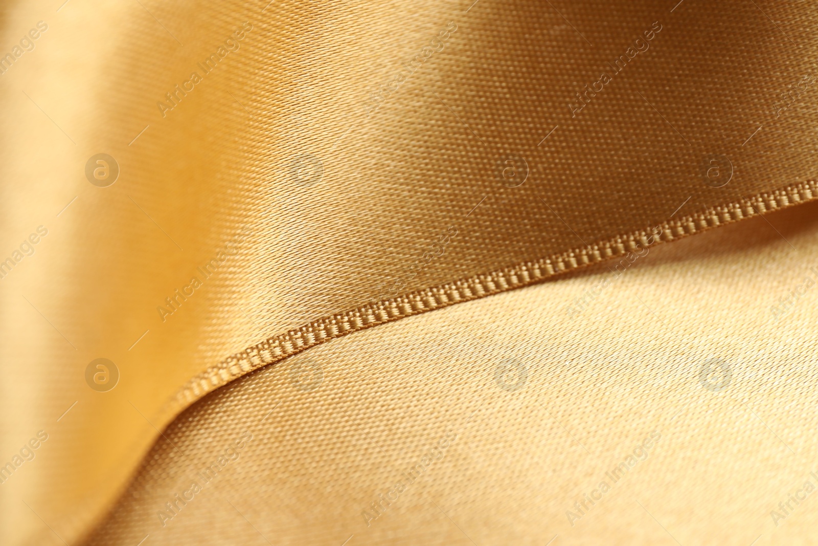 Photo of Beautiful golden ribbon as background, closeup view