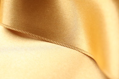 Photo of Beautiful golden ribbon as background, closeup view