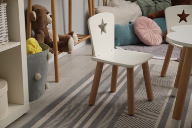 Photo of Small chairs, teddy bear and pillows in child room. Interior design