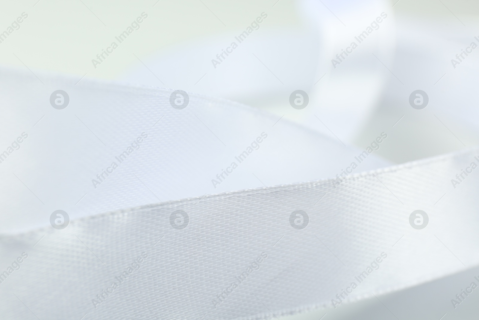 Photo of Beautiful white ribbon on light background, closeup