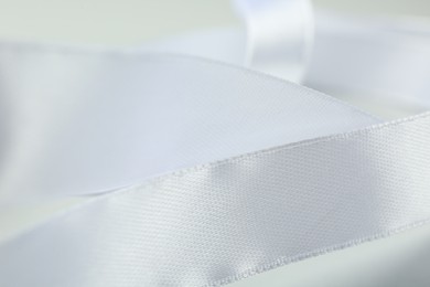 Photo of Beautiful white ribbon on light background, closeup