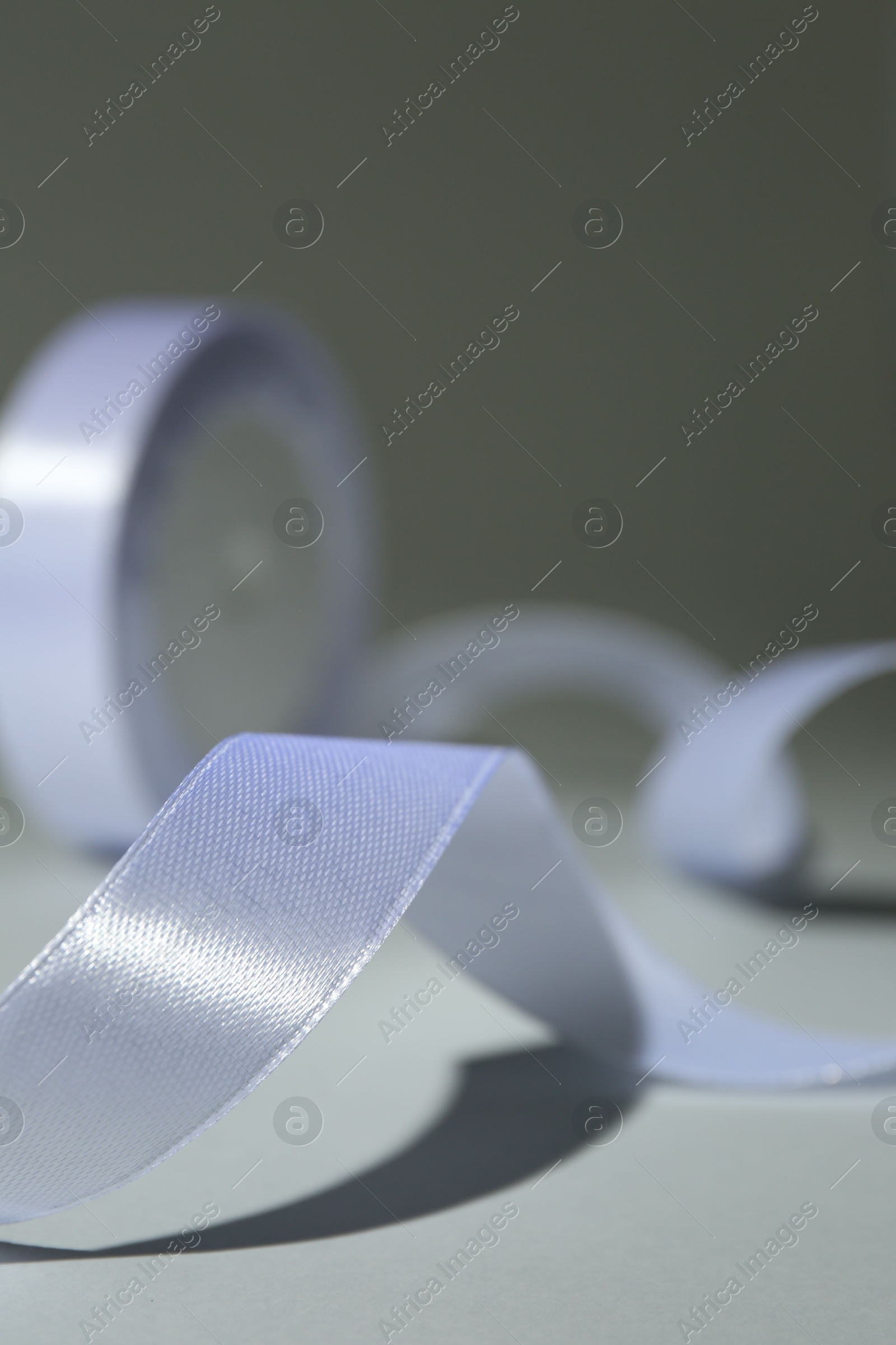 Photo of Beautiful white ribbon reel on gray background, closeup