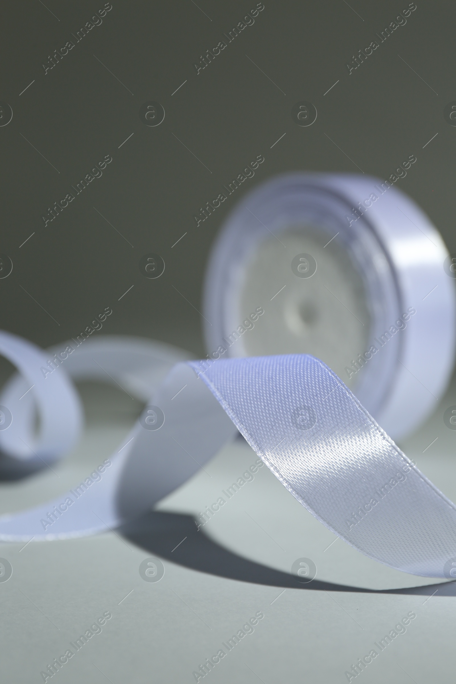 Photo of Beautiful white ribbon reel on gray background, closeup
