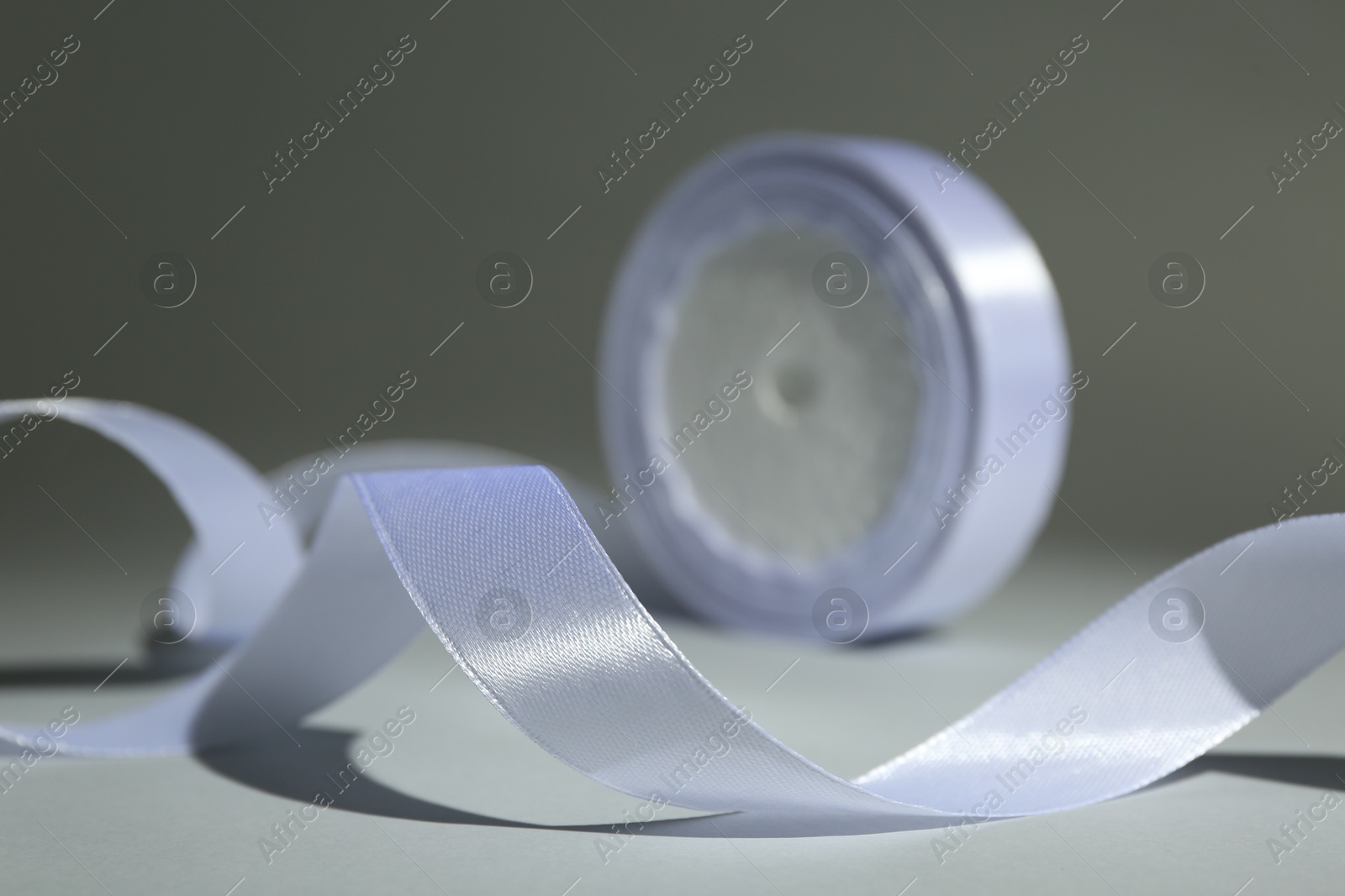 Photo of Beautiful white ribbon reel on gray background, closeup