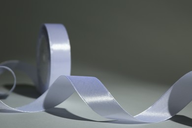 Photo of Beautiful white ribbon reel on gray background, closeup