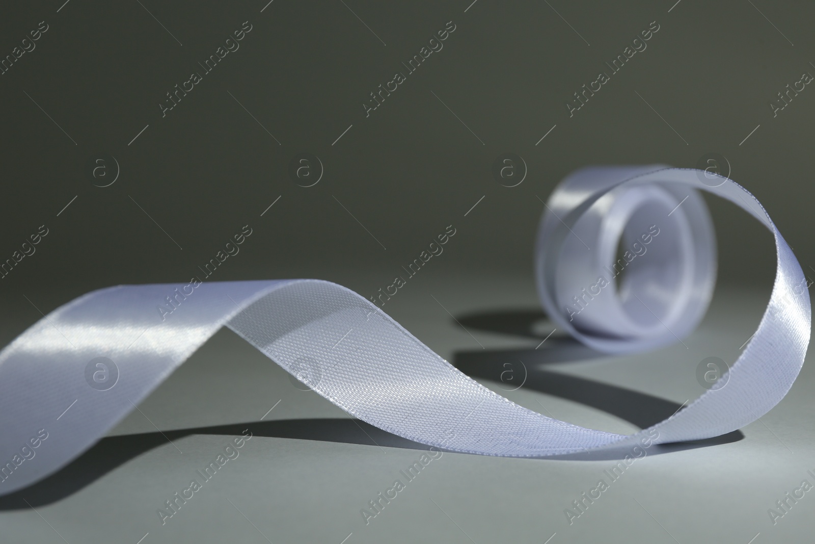 Photo of Beautiful white ribbon reel on gray background, closeup