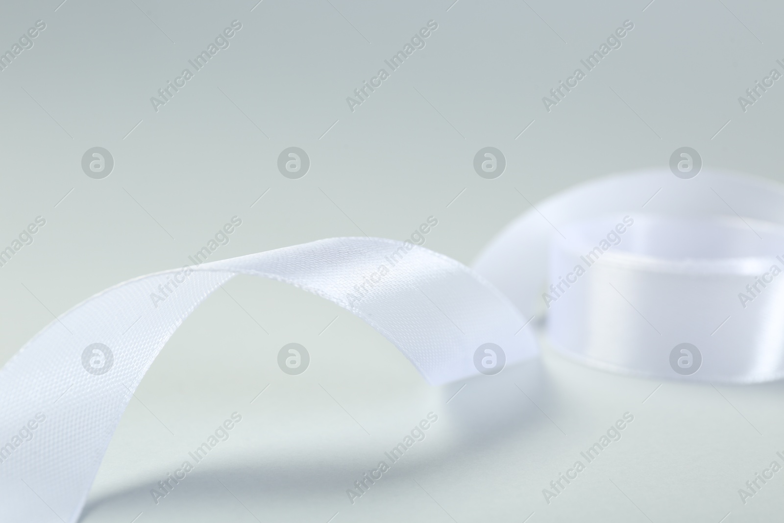 Photo of Beautiful white ribbon on light background, closeup