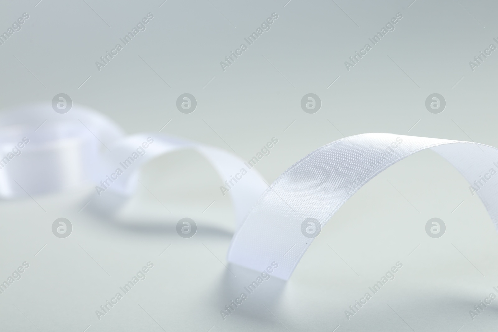 Photo of Beautiful white ribbon on light background, closeup