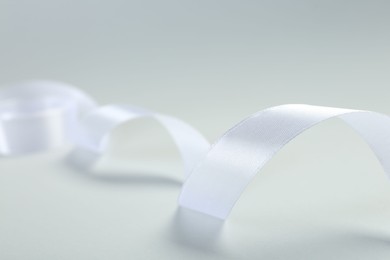 Beautiful white ribbon on light background, closeup